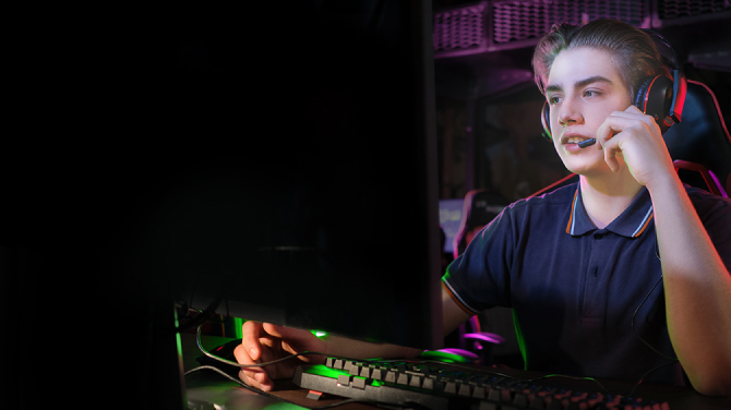 A gamer wearing a headset in front of a monitor. Blue light emission is 75% for conventional monitors, while it is 35% for OLED, emphasizing that it can maintain comfortable eyes during prolonged gameplay.