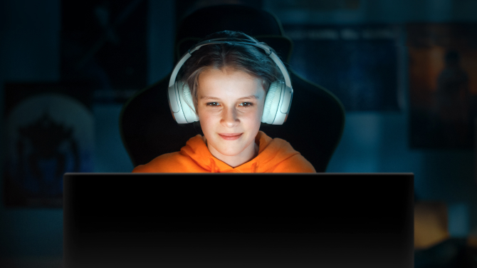 A girl playing a game in a dark room. Highlighting how OLED displays deliver optimal picture quality without glare both day and night, reducing eye strain for extended use.